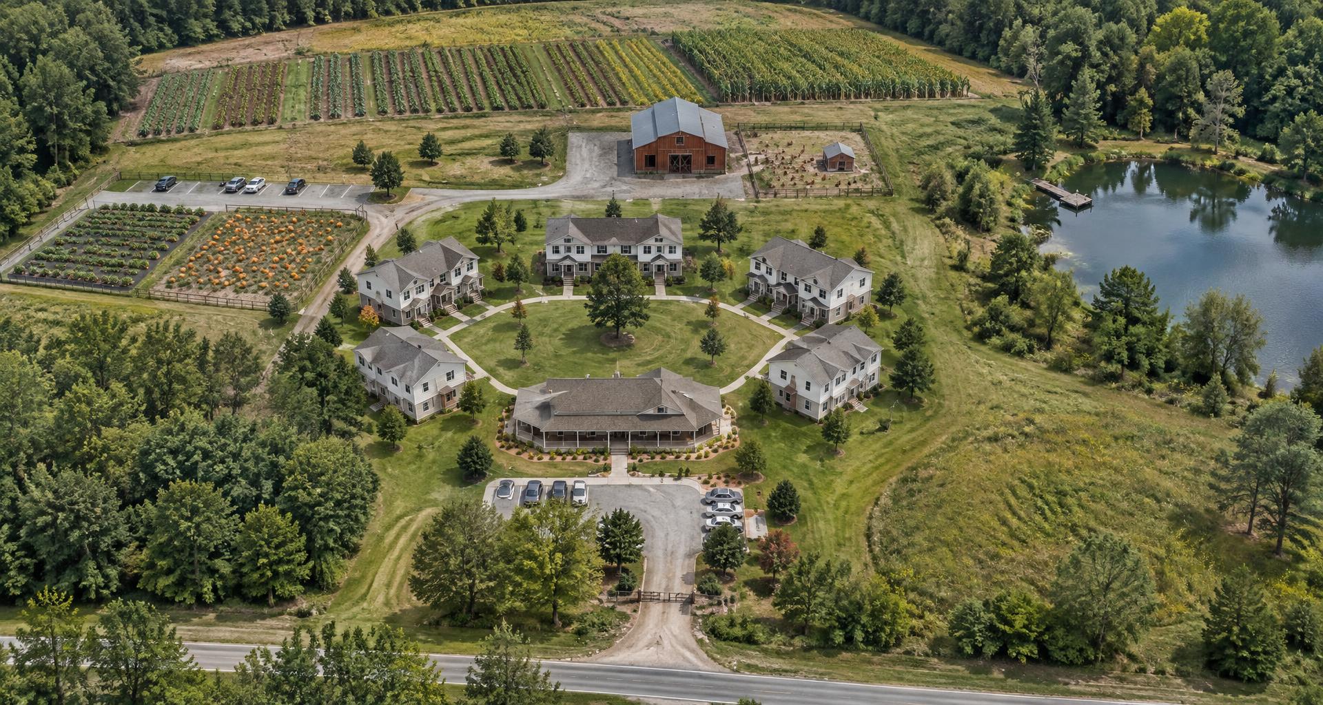 Architectural site plan rendering of the Veteran Transformation Housing campus: community building, five residences around a green, barn, crop fields, garden patches, and a fishing pond